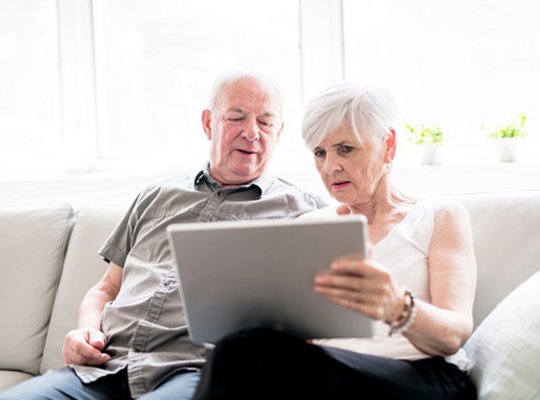 Couple Sitting On Sofa Looking At Laptop Small