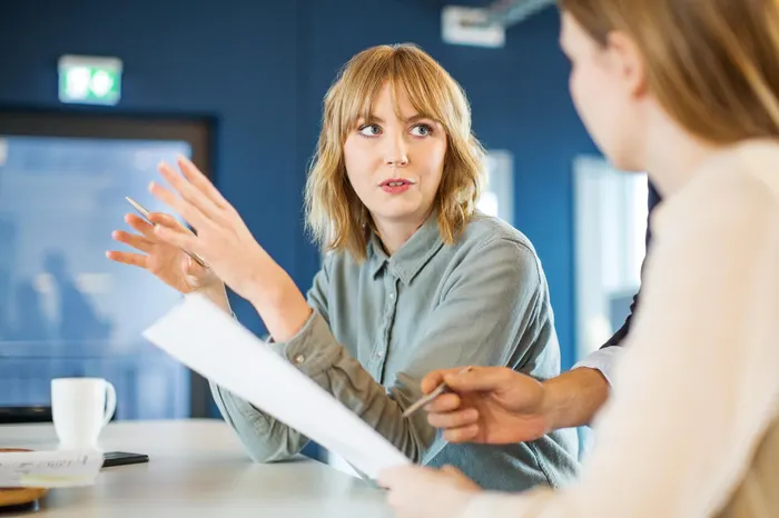 Two people in meeting holding papers