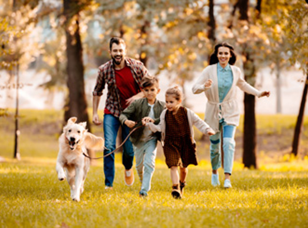 Family Running In Woods With Dog