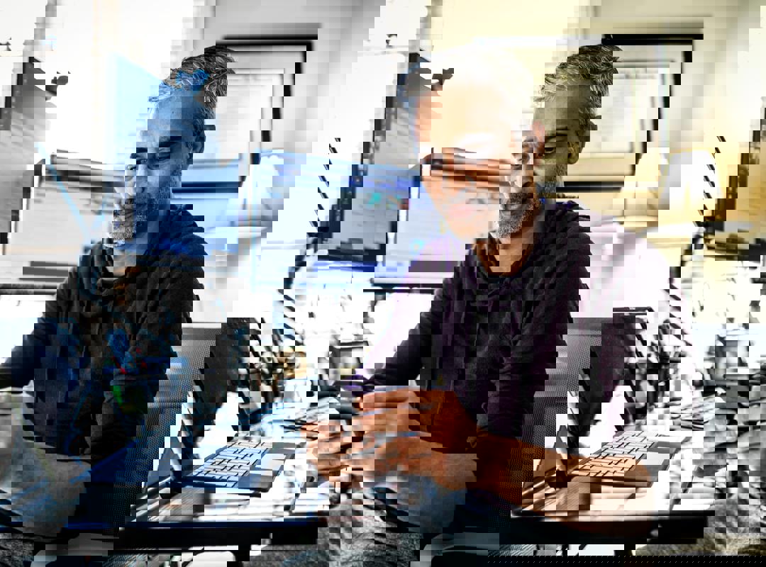 Man On His Phone At His Desk With Computers