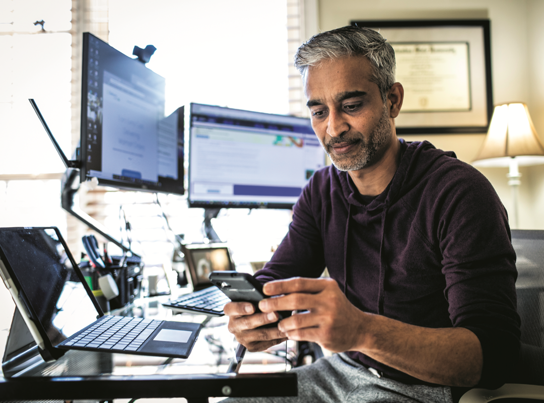 Man Sitting At His Desk With Multiple Devices Png