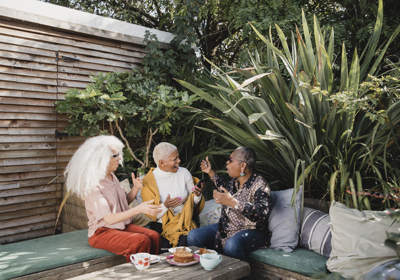Three People Talking In A Garden