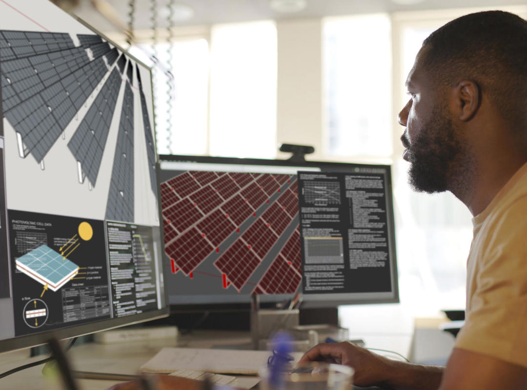 Man Looking At Computer With Solar Panels On Screen