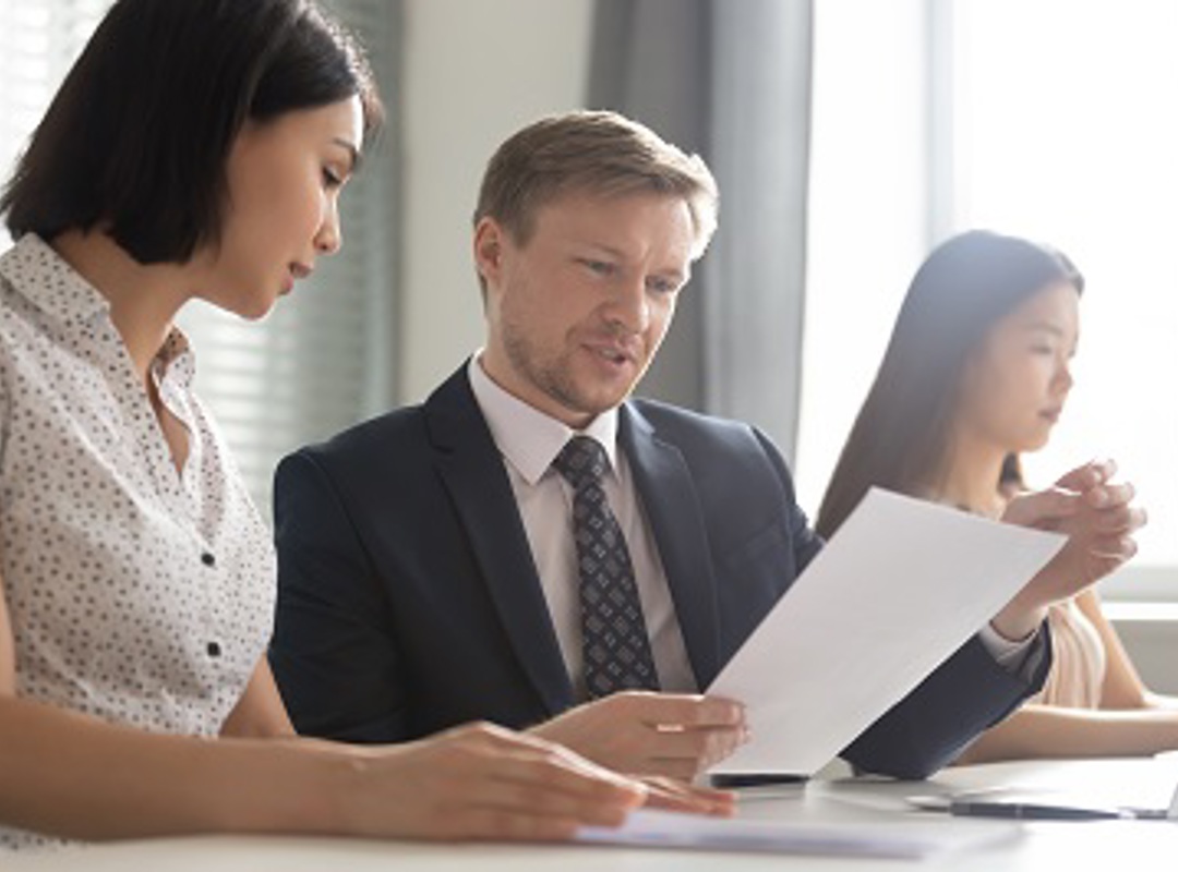 Three People Looking At Document 400X266