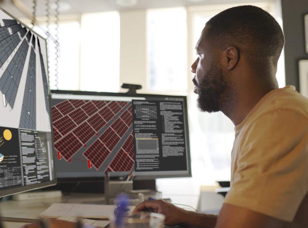 Man Looking At Computer With Solar Panels On Screen